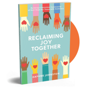 The book cover for “Reclaiming Joy Together” by Daphne Johnston, inlcludes an illustration of hands with hearts in the palms.