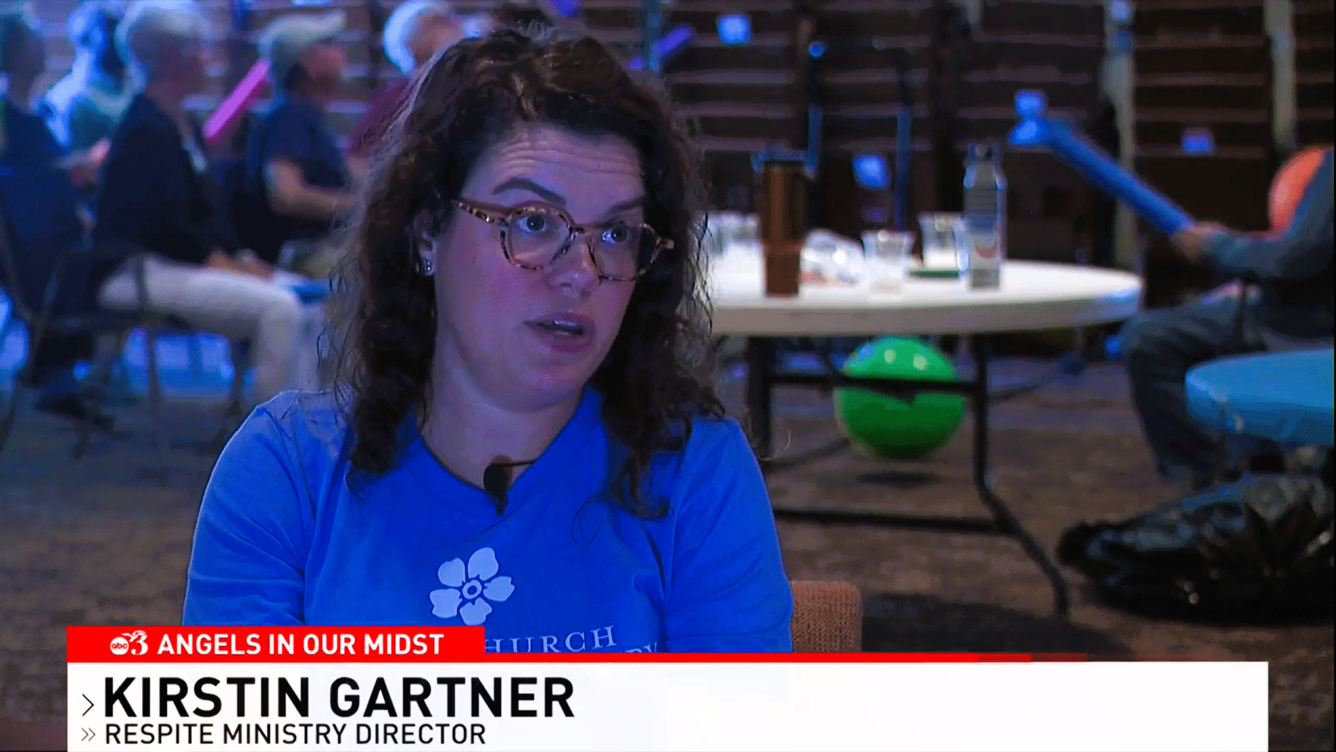 Kirstin Gartner, Respite Ministry Director, interviewed for ABC news program with participants engaging in activities in the background.
