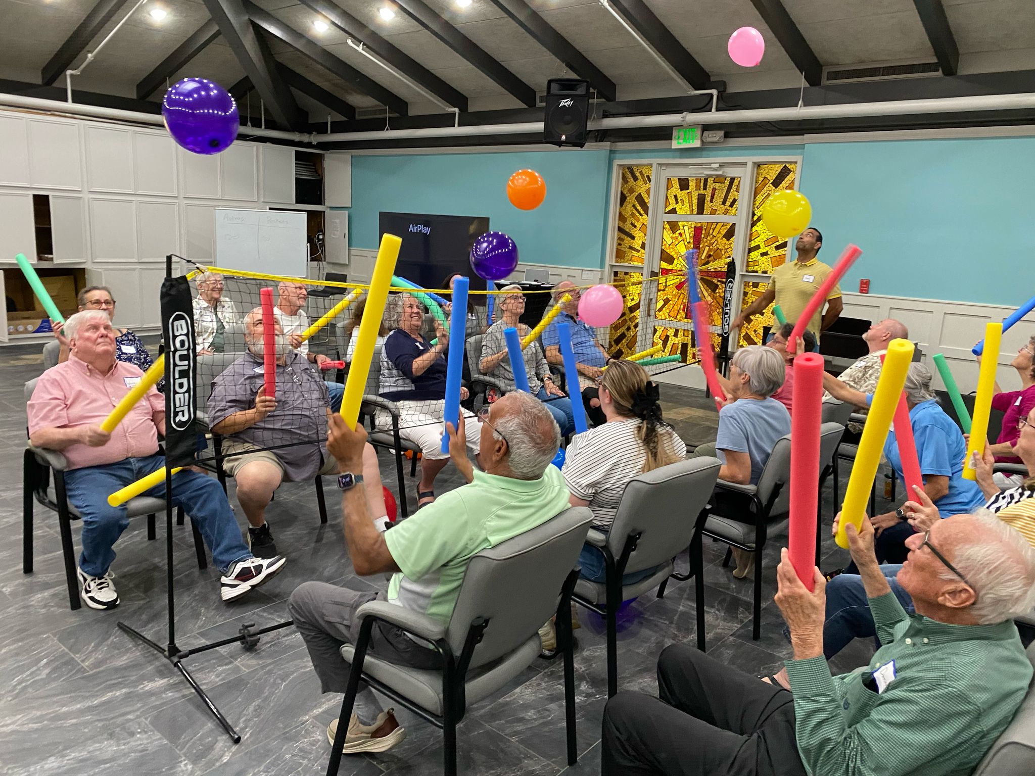 Apollo Balloon Volleyball Volunteers and participants engage in a playful activity with pool noodles and balloons during the Apollo: Respite for All event at St. Thomas the Apostle Episcopal.