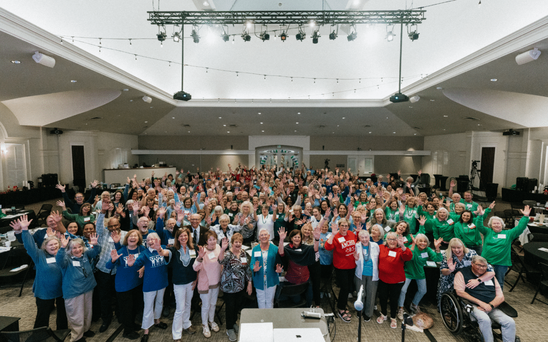 Large group of attendees posing on stage during a Respite for All annual meeting
